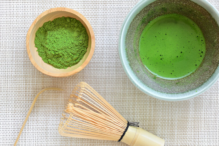 Matcha powder, whisk, and bowl of green tea